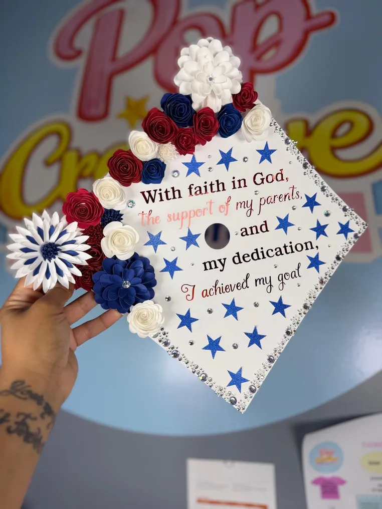 Birrete de graduación blanco con flores rojas, blancas y azules
